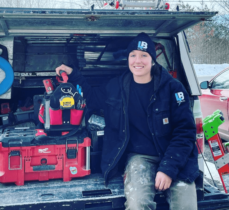 LB Electrician sitting on work truck tailgate wearing LB winter hat and coat