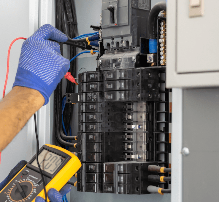 Electrician wearing blue shielded gloves testing circuit breakers in commercial panel outlet