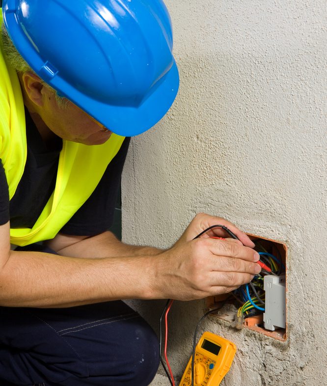 Electrician uses a circuit tester in wall insert relay box