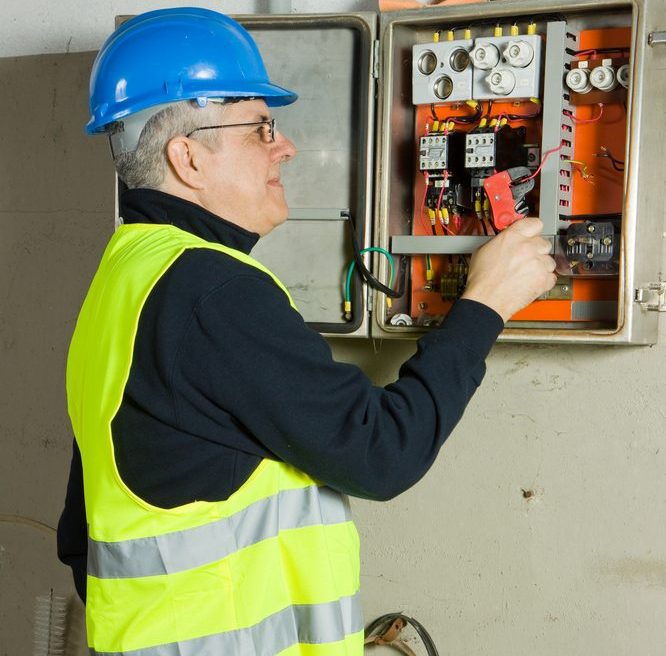 Electrician inspects and test circuits in an electrical relay box